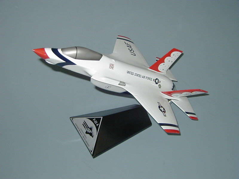 A scale model of a Lockheed F-35 Joint Strike Fighter, predominantly white with red and blue accents, placed on a display stand.
